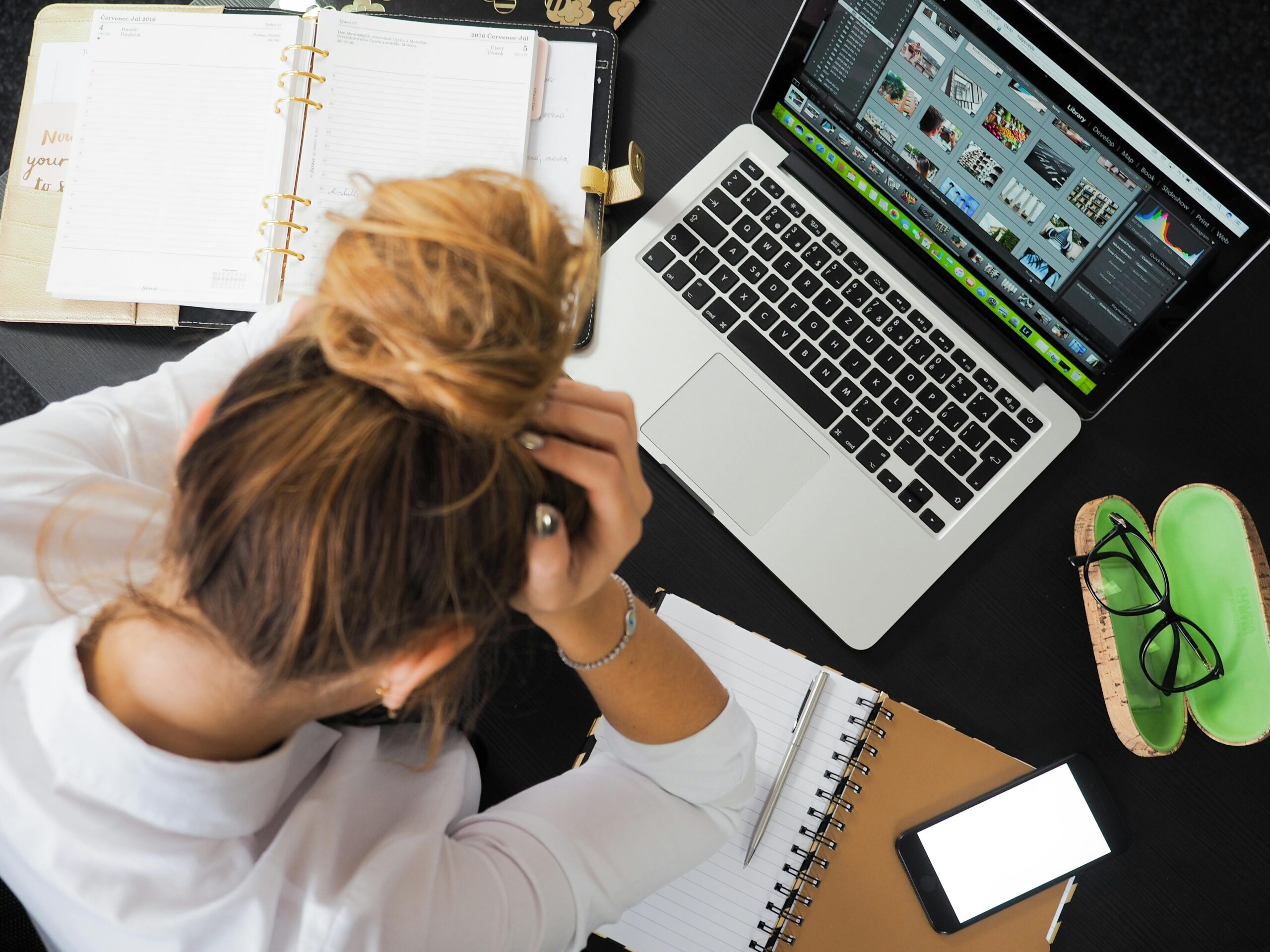 frustrated woman holding head in hand while looking down at computer