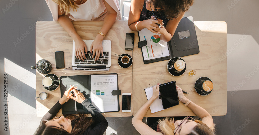 Four Women Sitting at a Table Working on Computers